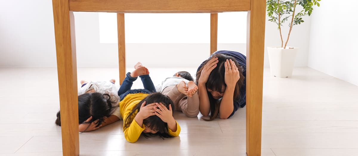 Enfants se protégeant d'un tremblement de terre en se cachant sous une table.