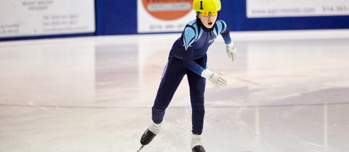 Enfant sur une patinoire intérieure habillé pour pratiquer le patinage de vitesse