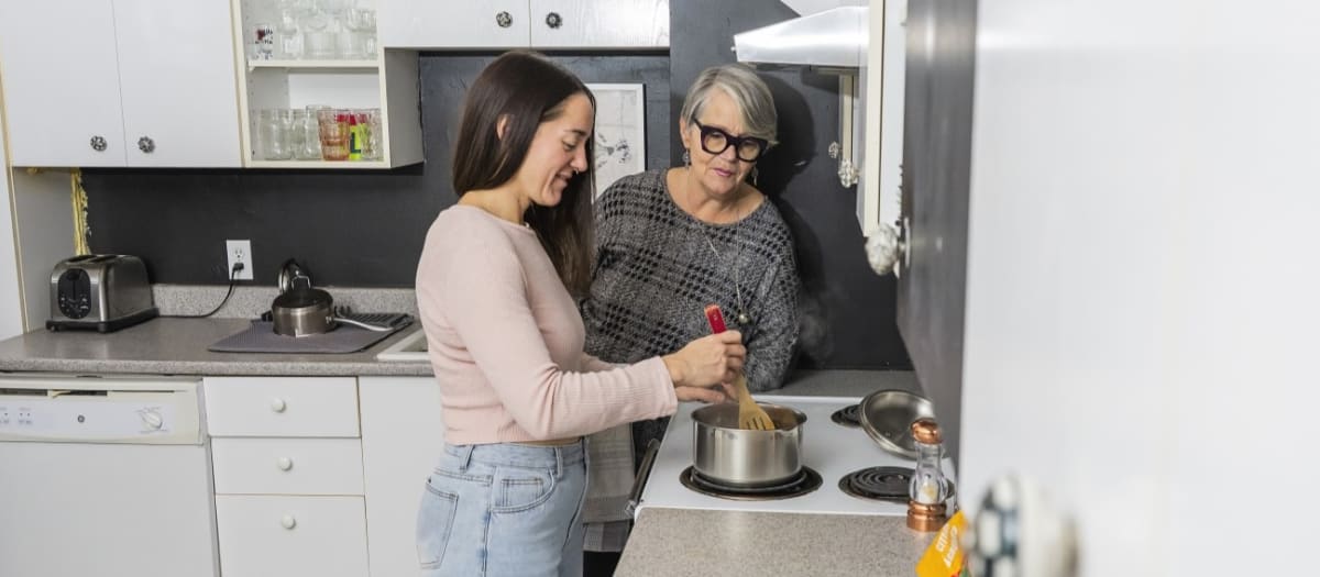 Deux femmes se tiennent près de la cuisinière dans une cuisine propre et bien rangée