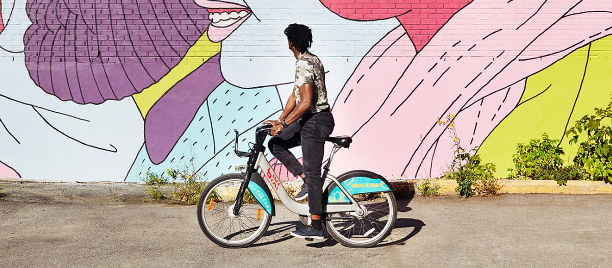 Cycliste qui admire une murale colorée.