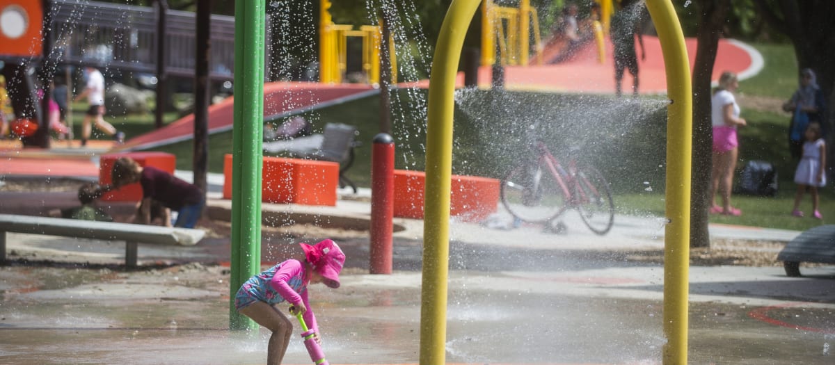 Photo d'une jeune enfant qui s'amuse sous les jets d'eau