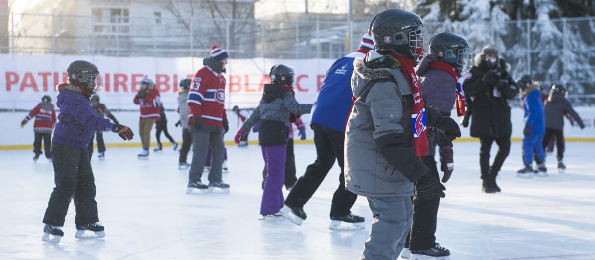 Photo de jeunes et moins jeunes patinant sur la patinoire Bleu Blanc Bouge du parc De Mésy par une froide journée d'hiver