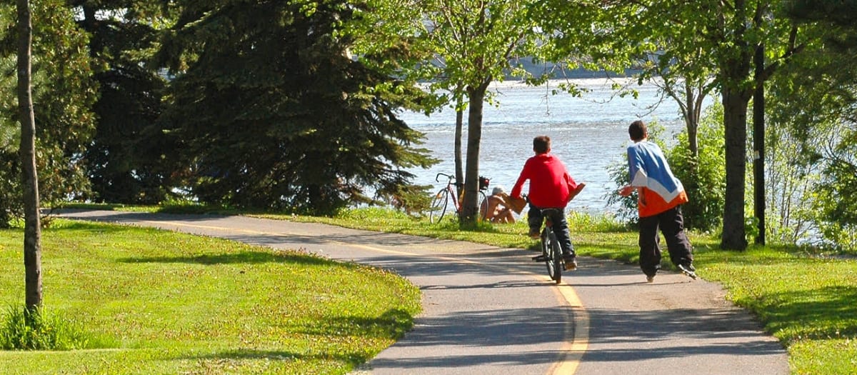 Des jeunes roulent sur une piste cyclable près de la rivière des Prairies.