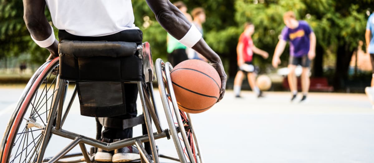 Personne en fauteuil roulant de dos tenant un ballon de basketball