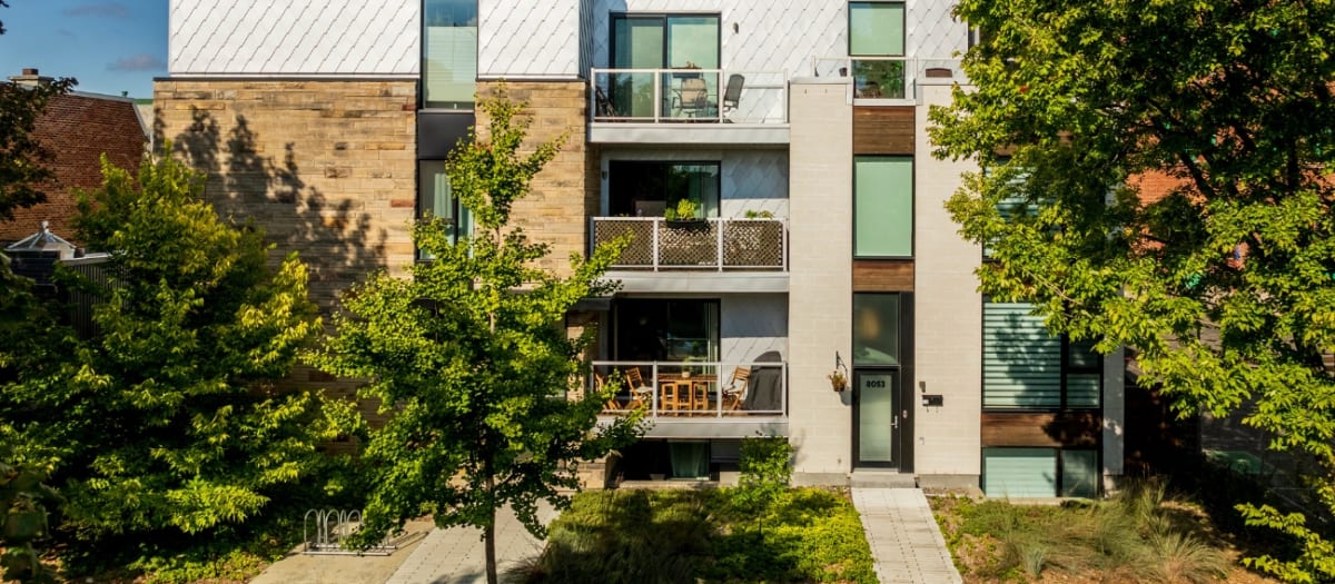Vue d'un immeuble moderne de 3 étages entouré de verdure