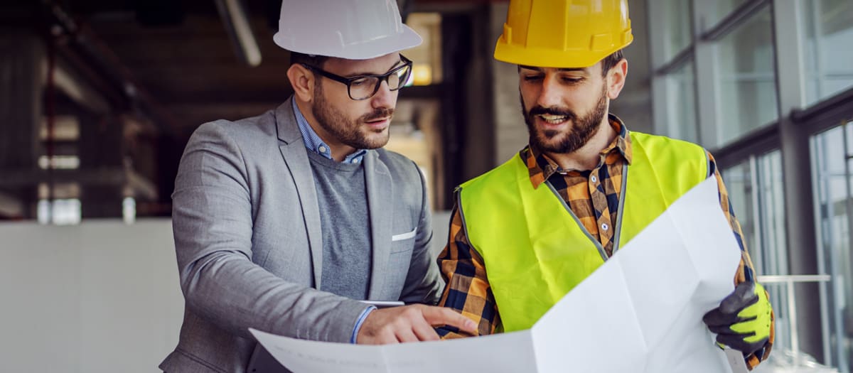 Workers discussing a plan in a building udergoing renovation.
