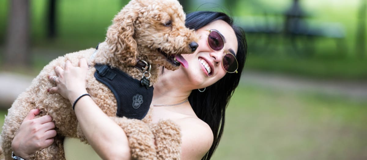 Une femme tient son chien dans ses bras en souriant.