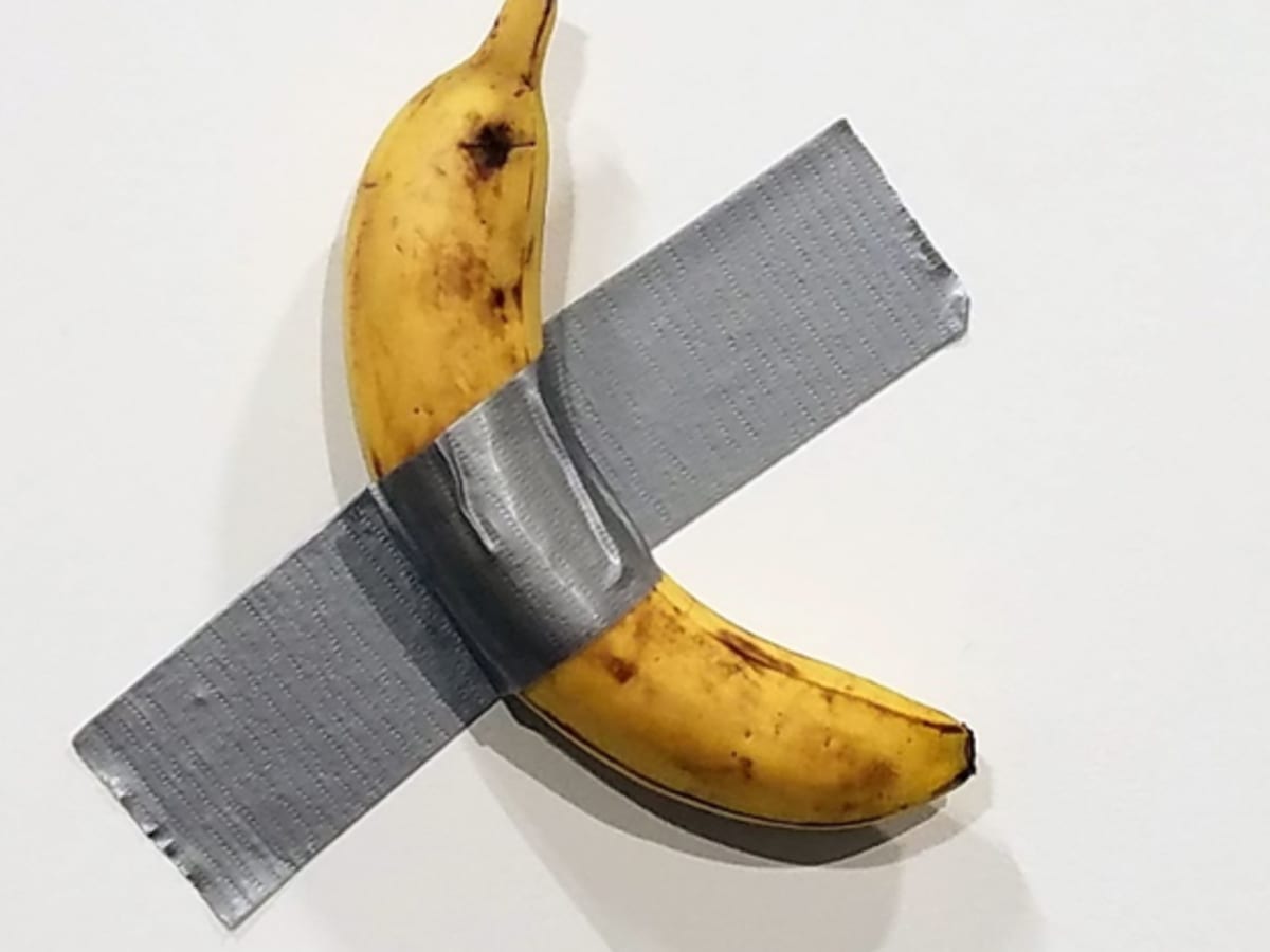 une banane collée avec du tape sur un mur blanc
