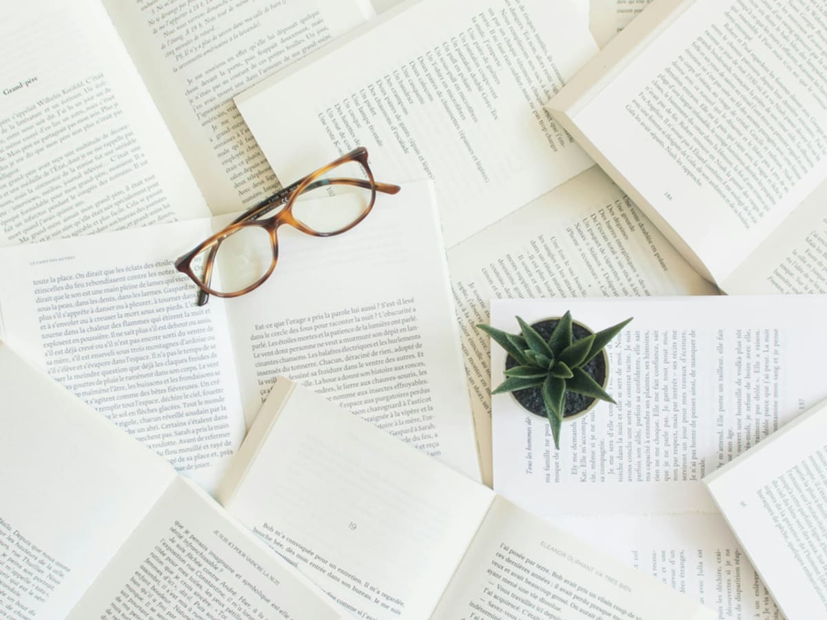 Photo de livres ouverts en pile avec une paire de lunettes déposée