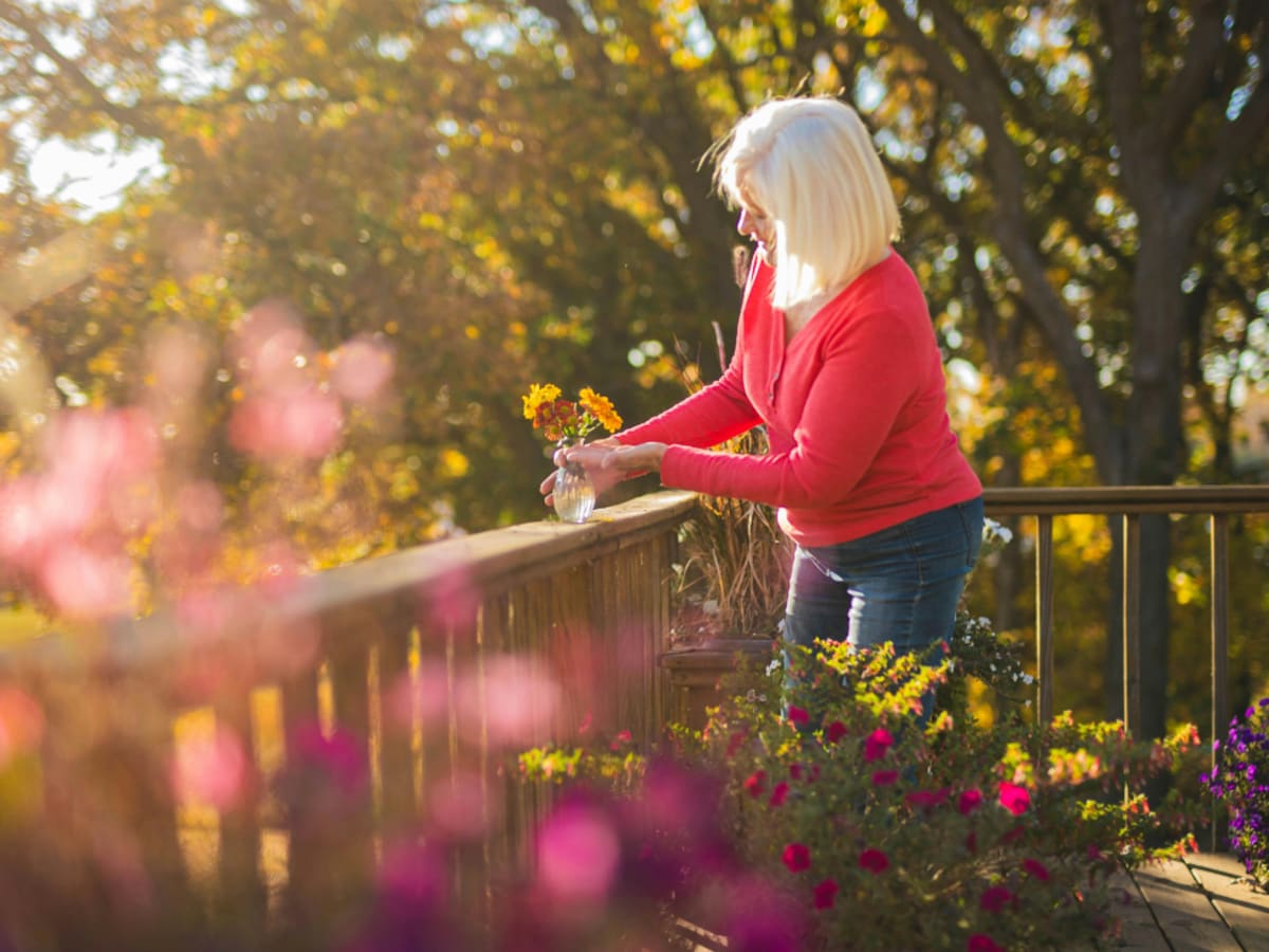 Femme mettant un pot de fleur sur son balcon