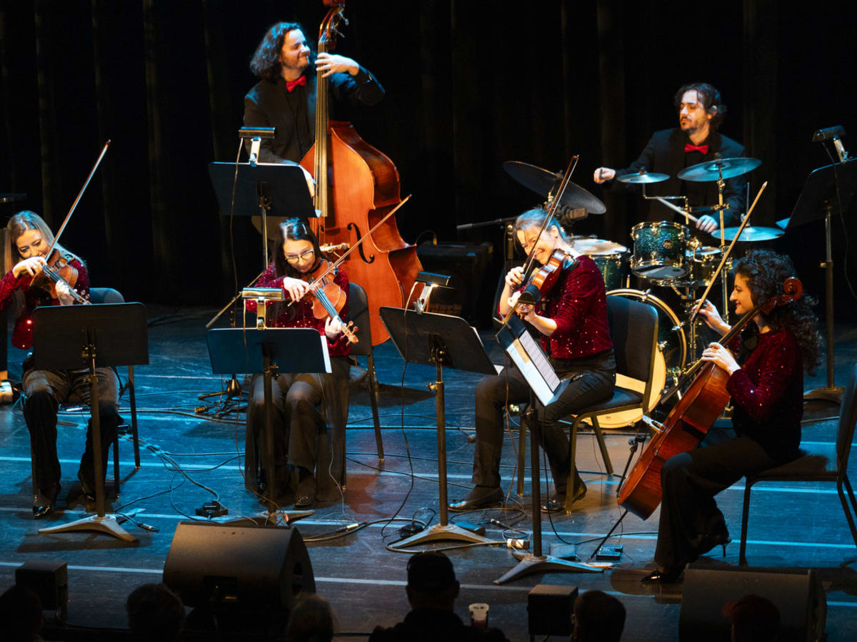 La photo montre le groupe de musiciens et musiciennes sur scène