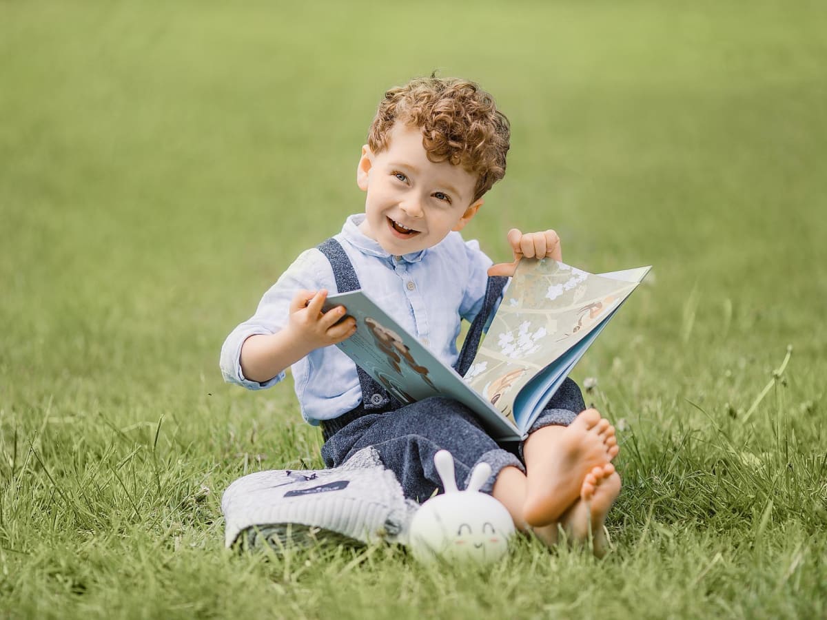 Enfant avec un livre assis sur le gazon