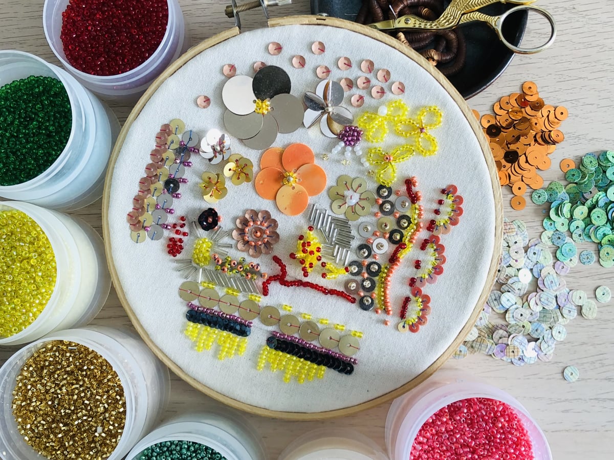 Une photo de fleures en perlage entourés de bols de perles colorées