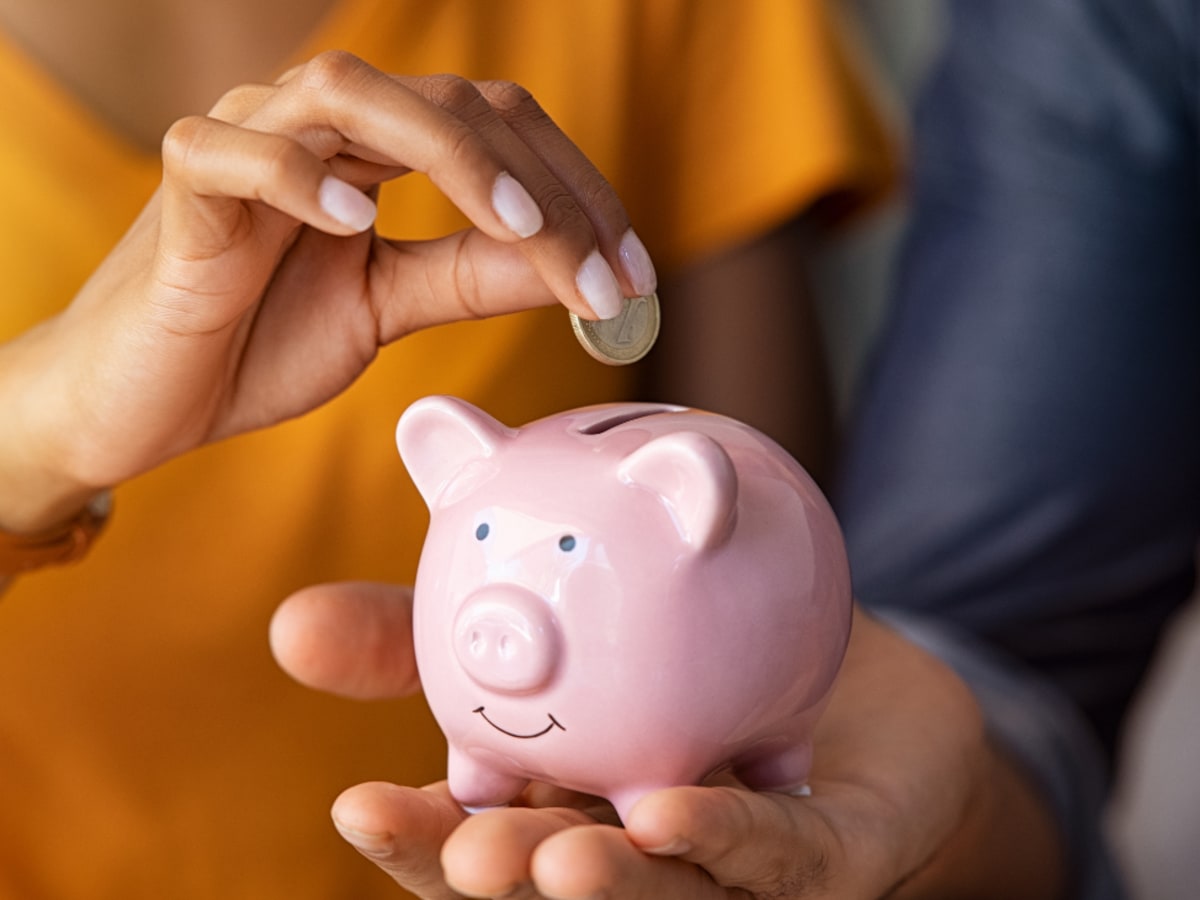 main de femme déposant un sous dans une banque tenue par un homme