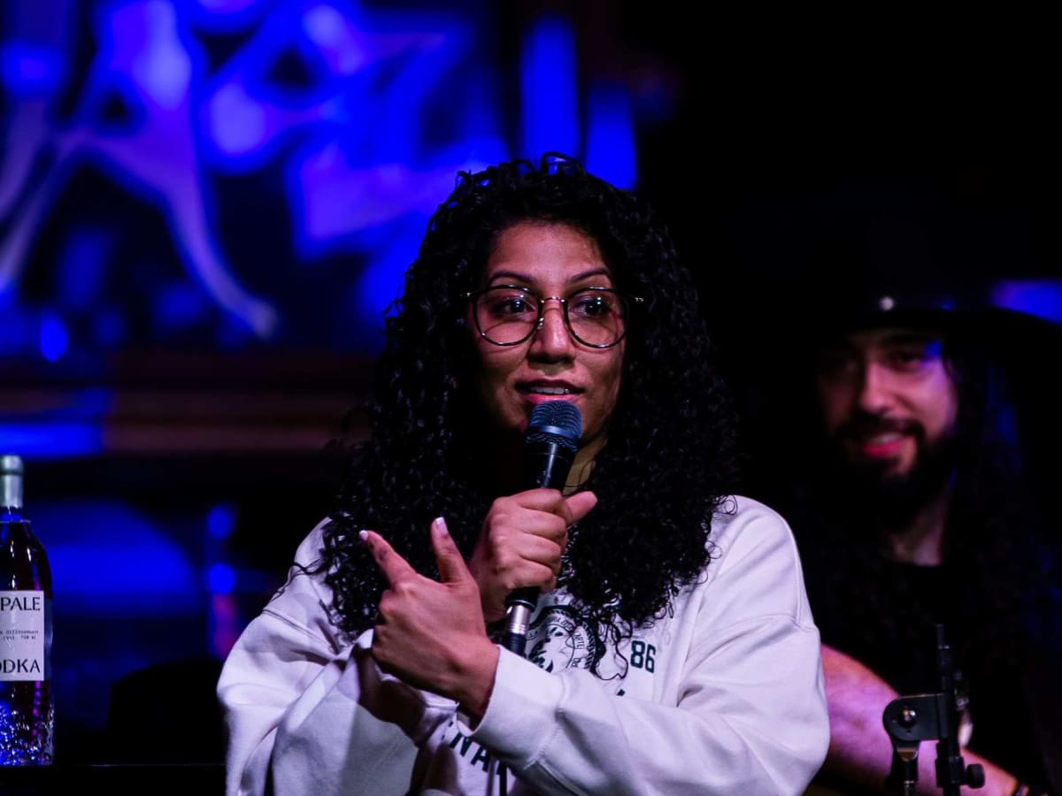 Femme au micro avec un guitariste derrière elle pendant un spectacle d'humour