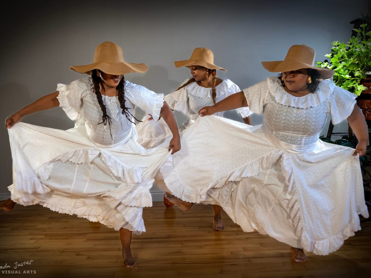 La photo présente trois danseuses de la troupe Mapu Ginen en robe blanche et chapeau de paille