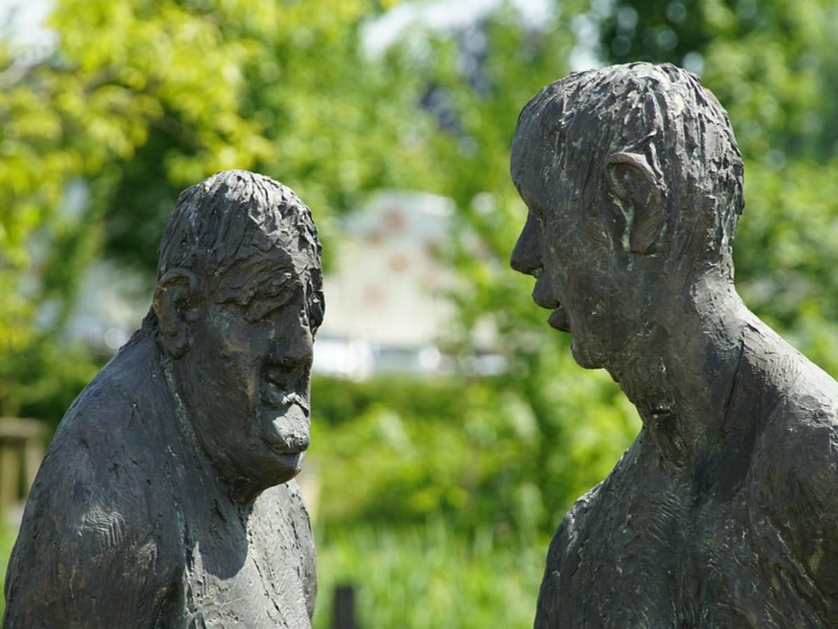 Copilot said: Sculpture représentant deux personnes en discussion dans un espace vert.