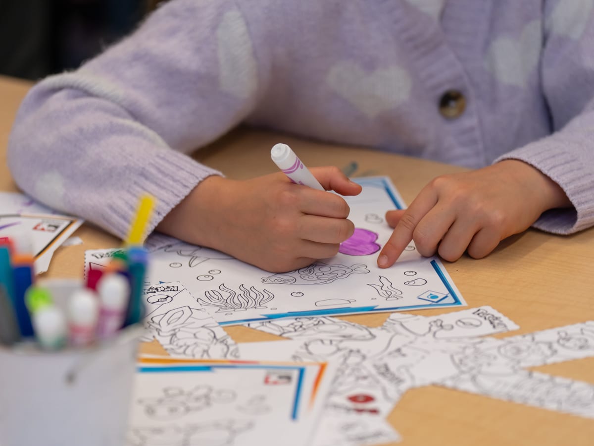 Un enfant dessine sur une table à la bibliothèque Frontenac.