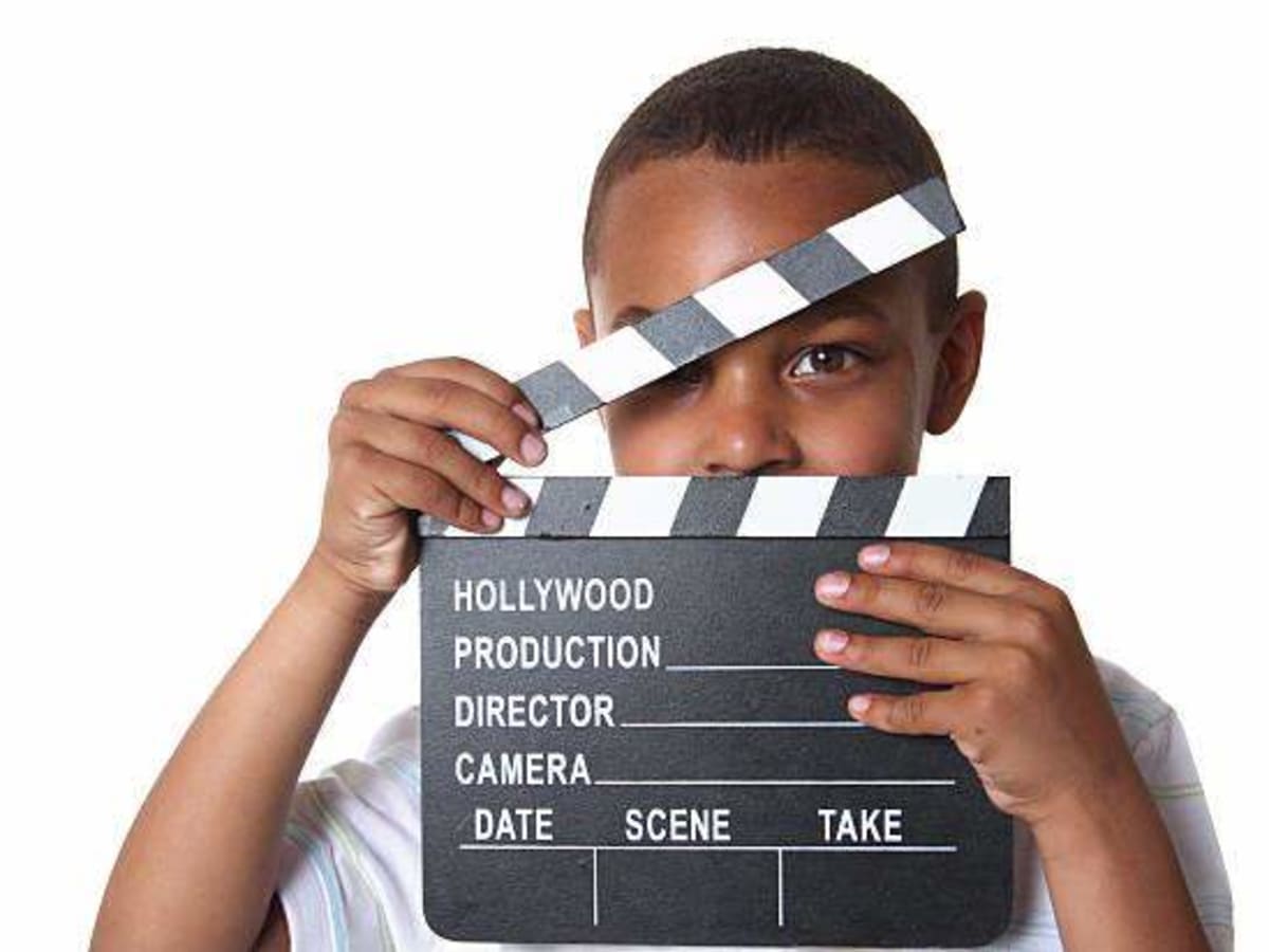 Une photo d'un jeune tenant un clap de cinéma