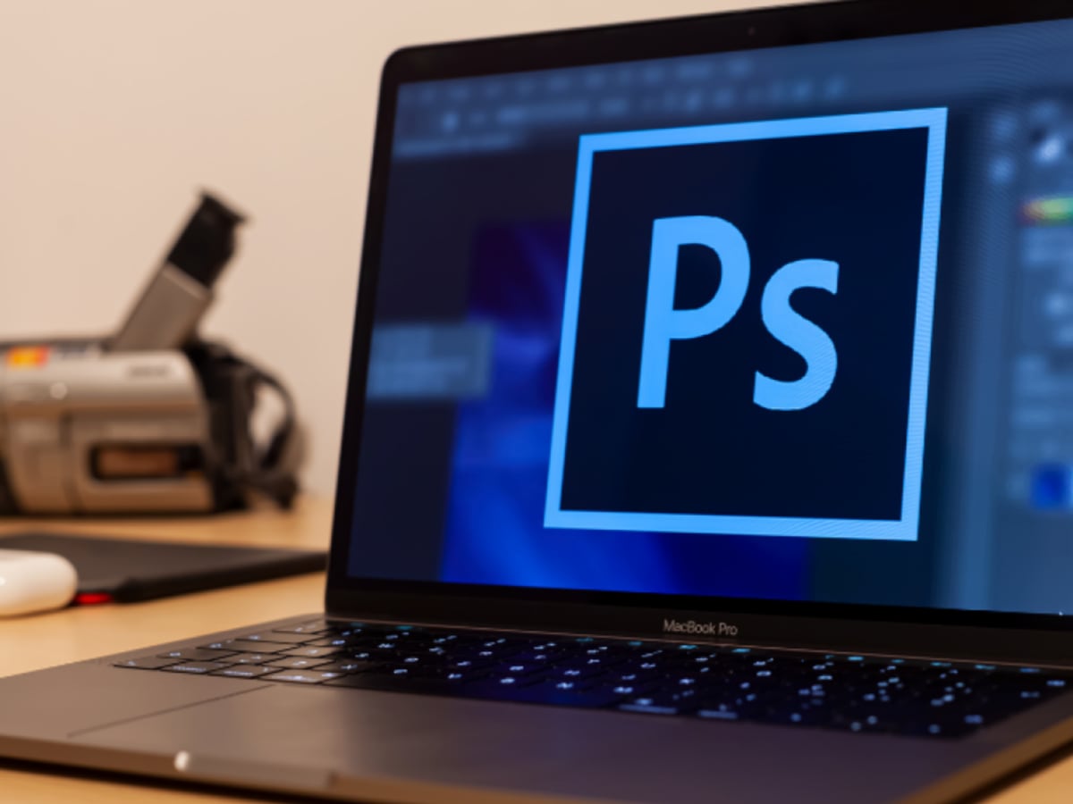 Ordinateur portable sur une table avec logiciel Photoshop affiché sur l'écran.