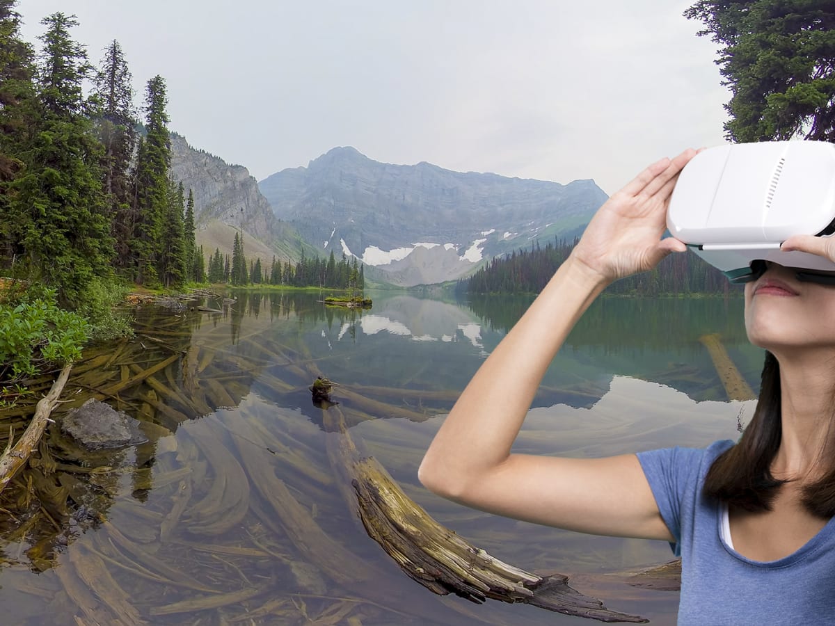 Une femme contemple un paysage forestier avec des lunettes de réalité virtuelle.