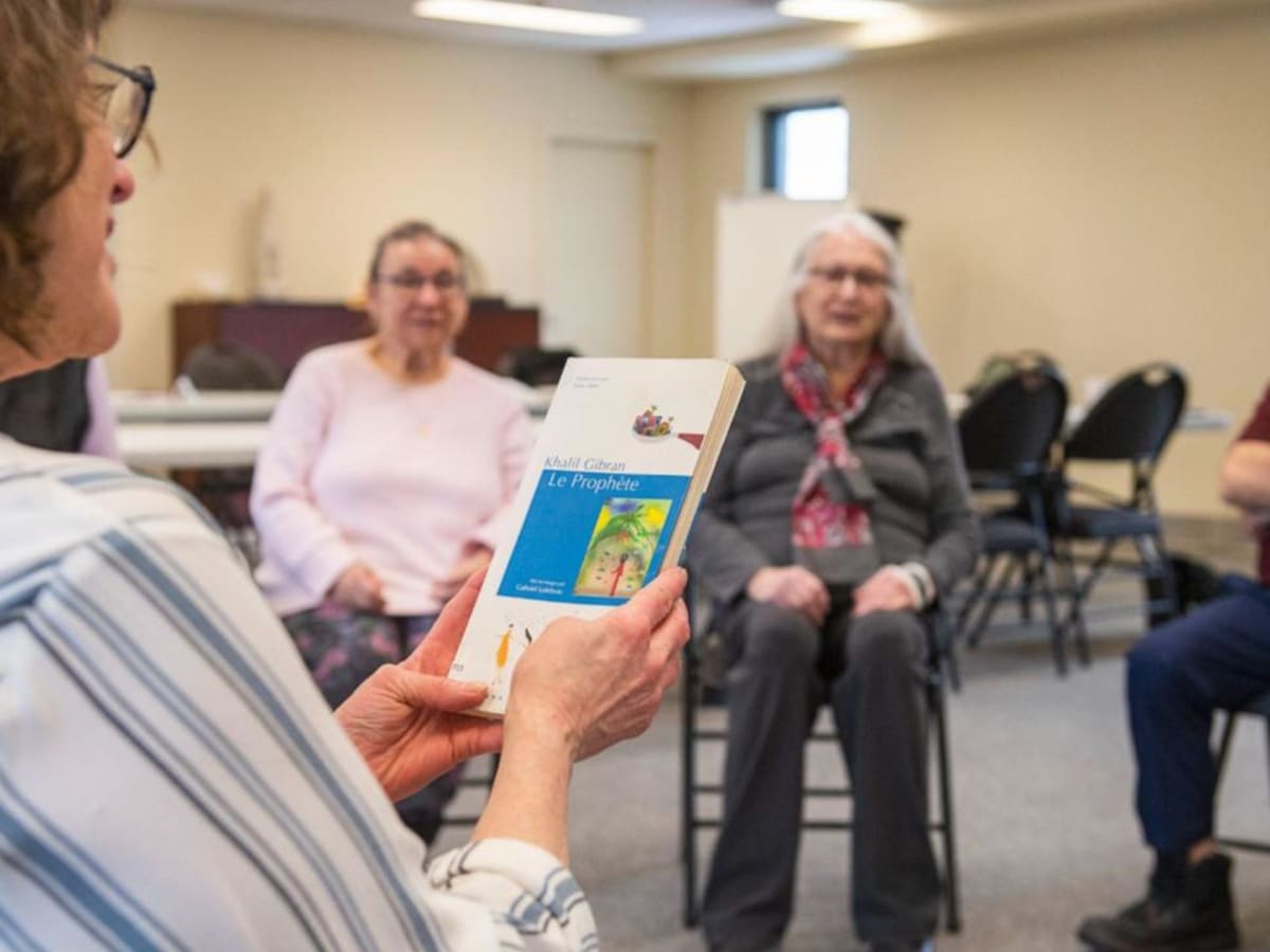 Une femme lit un livre à des personnes âgées