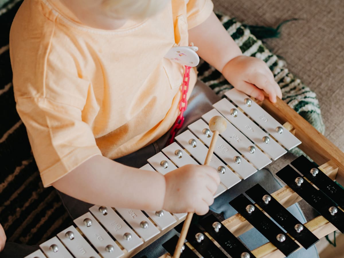 Un enfant joue du métallophone avec une baguette.