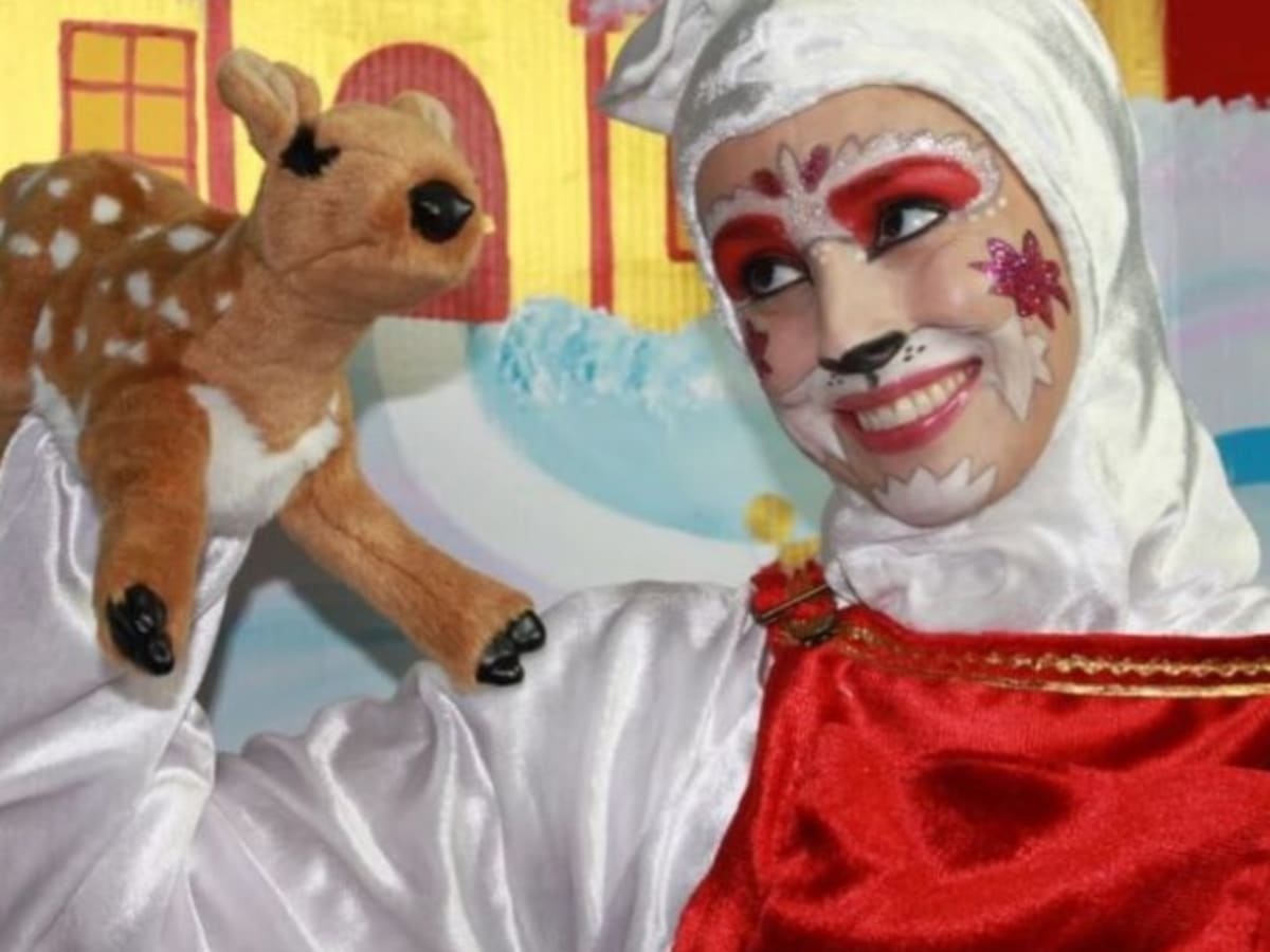 Une personne déguisé en chat tient une marionnette d'une biche dans sa main