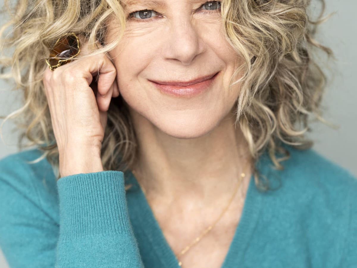 michele plomer qui se tient la tête et sourit