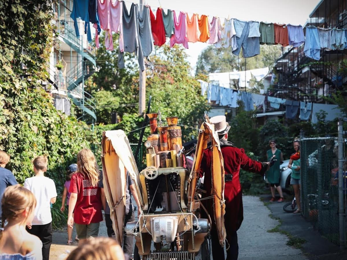 Artistes et citoyen(ne)s déambulent ensemble dans une ruelle.