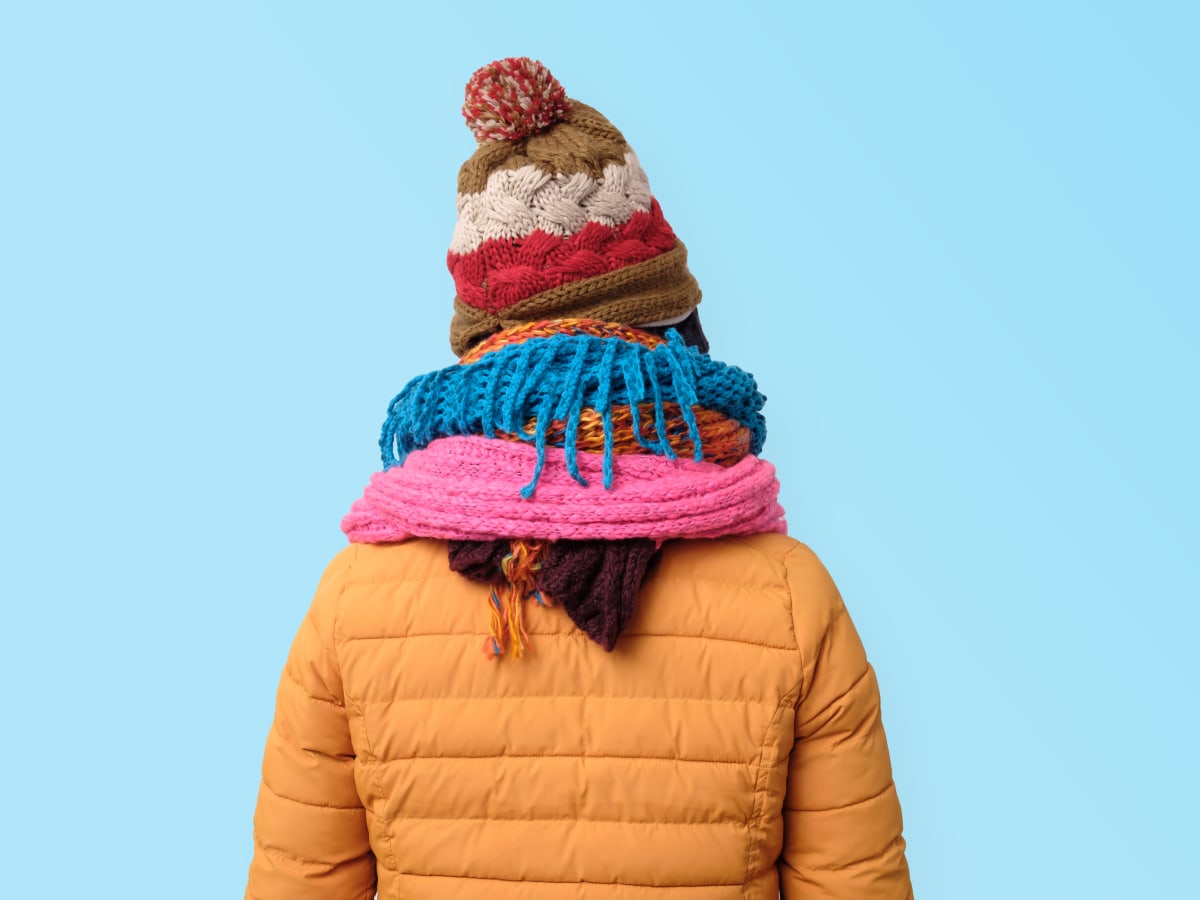 Une photo d'une personne de dos portant un manteau, des foulards et une tuque