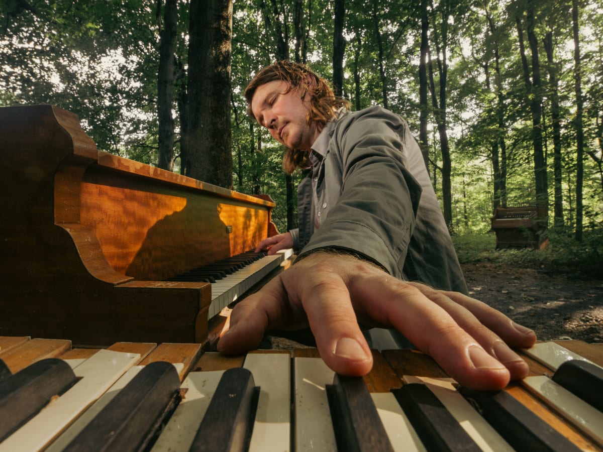 artiste Roman Zavada jouant du piano dans une forêt