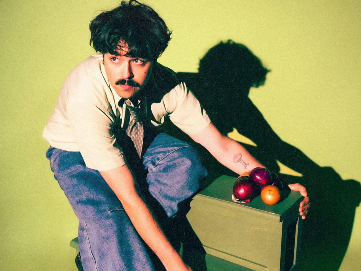Portrait artistique en studio d’une personne éclairée par un halo vert créant une atmosphère visuelle rétro et contrastée.