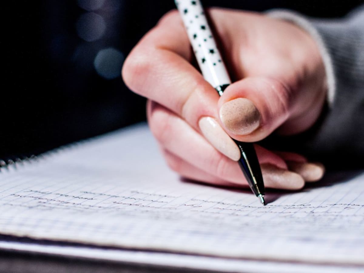 Une personne en train d'écrie au stylo-bille dans un cahier.