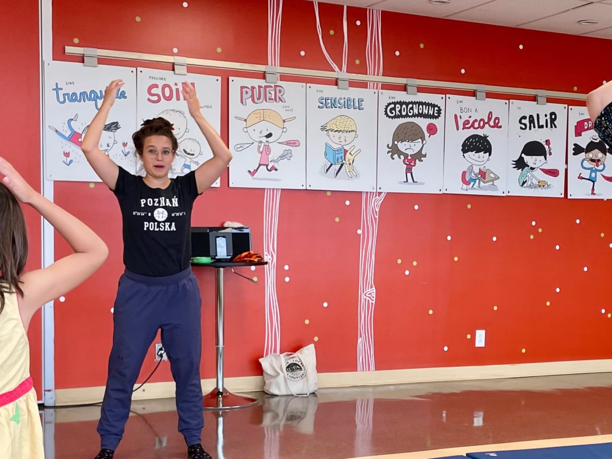 Une animatrice fait des gestes avec ses bras devant quelques personnes.