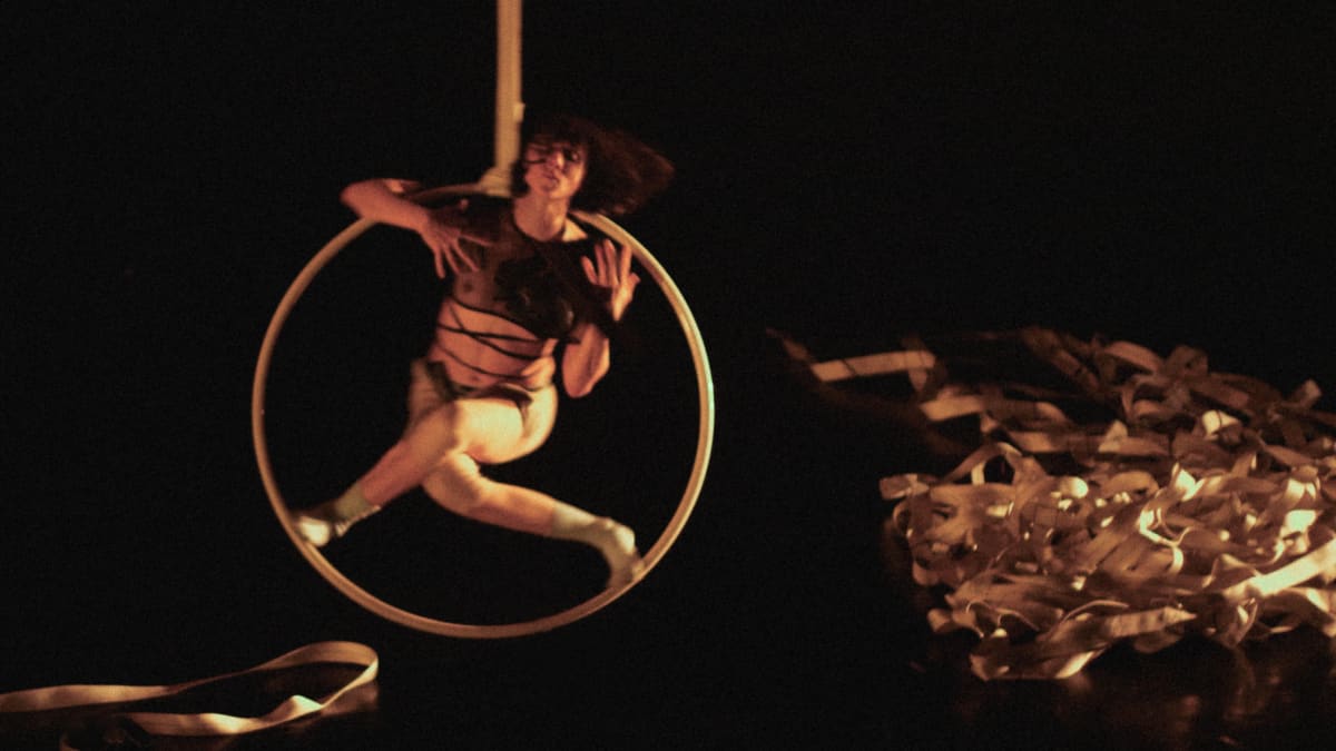 Acrobate avec les jambes croisées, dans un cerceau en mouvement.