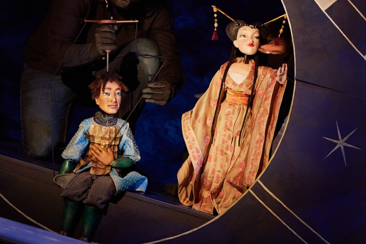 Marionnettes manipulées sur scène incarnant des personnages dans une scénographie théâtrale riche en détails et costumes.