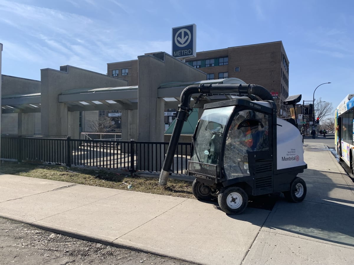Une voiturette-aspirateur aux abords d'un édicule de métro.