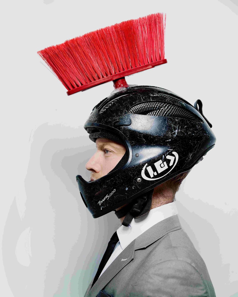 Homme de profil avec un casque de moto sur la tête comportant du balai dessus