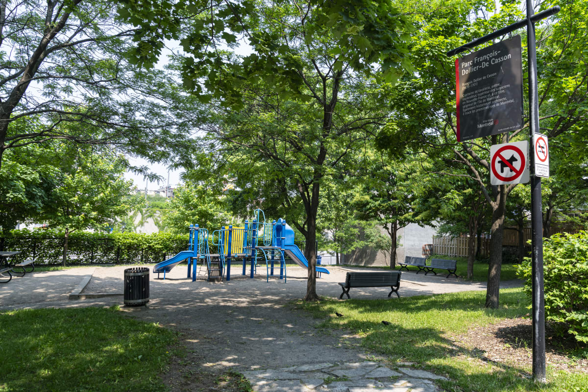 Aire de jeux du parc François-Dollier-de-Casson ombragée par de grands arbres.