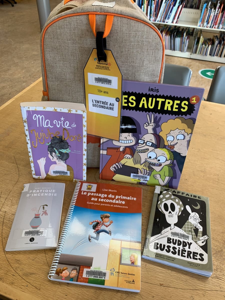 Trousse thématique de bibliothèque sur la transition vers le secondaire, avec un sac et plusieurs livres exposés sur une table.