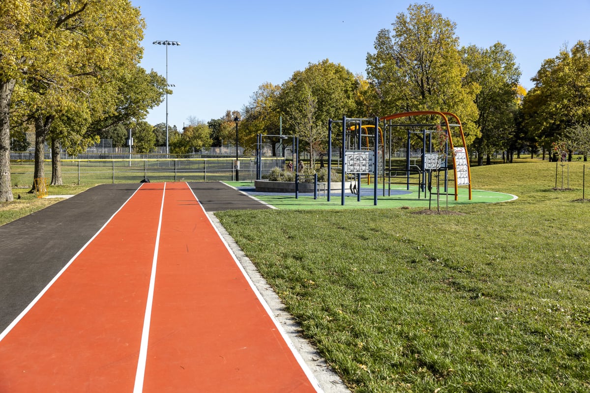 Photo montrant deux couloirs d'une piste d'athlétisme peints en rouge. À côté, on voit la zone d'exercice extérieure et le début d'une plaine gazonnée.
