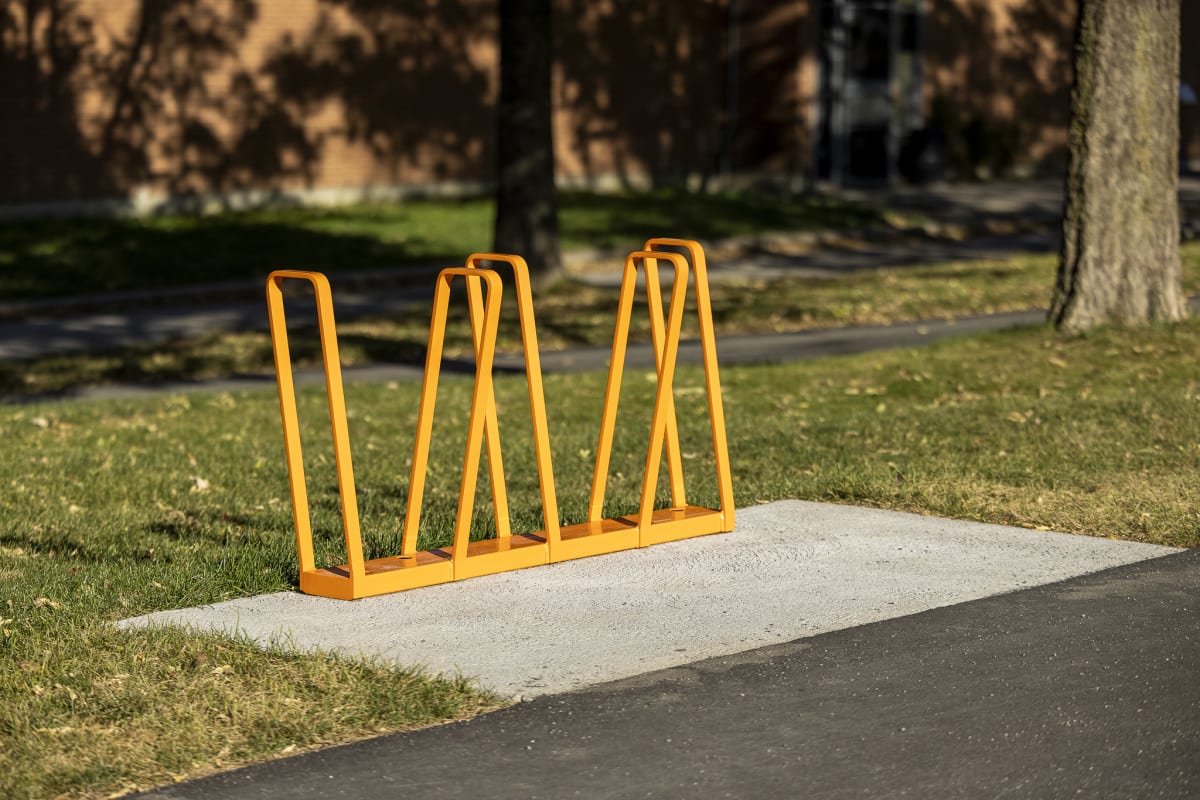 Photo des supports en métal de couleur jaune installés sur une plaque de béton à côté d'un espace gazonné