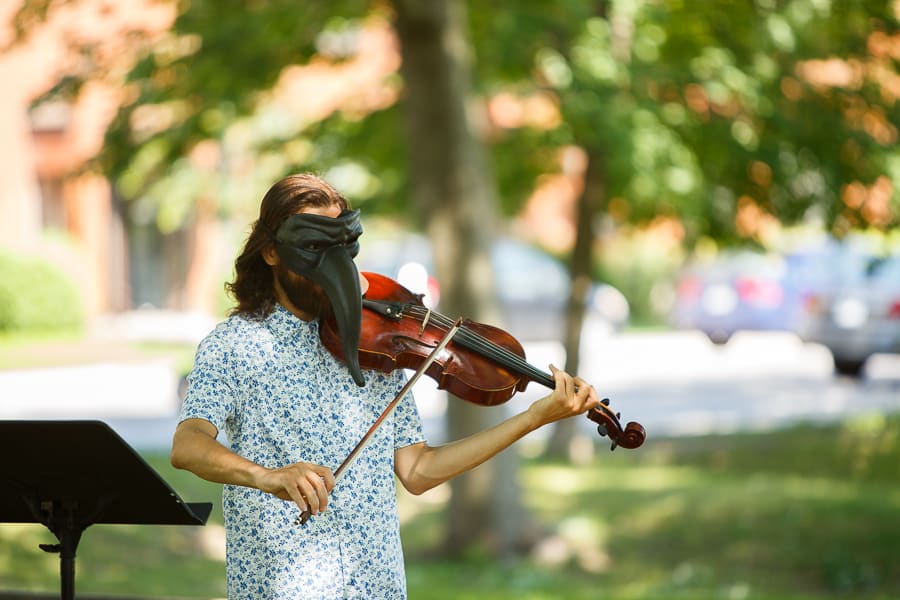 Spectacle ou un homme joue du violon l'été dans un parc, il porte un masque étrange et fantastique