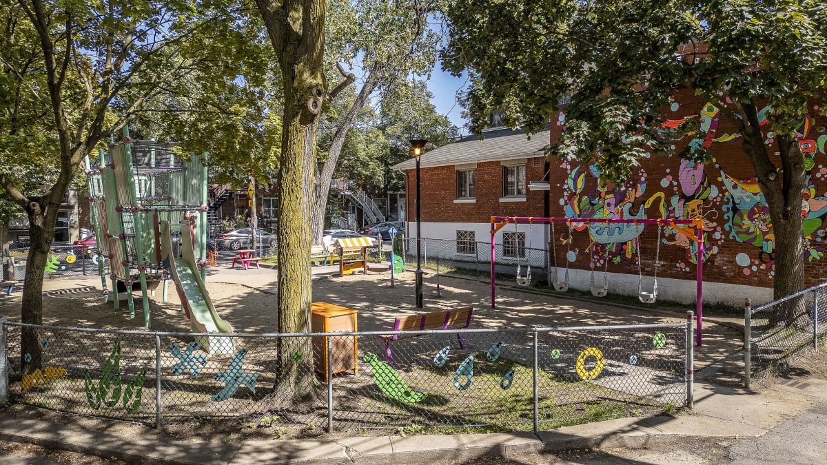 Photo montrant le parc dans sa globalité avec la murale en fond et l'installation artistique sur la clôture