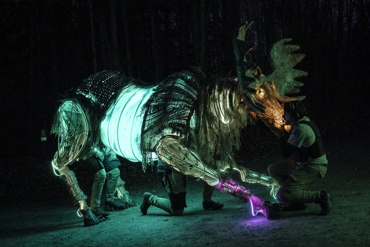 Homme agenouillé devant un faux caribou.