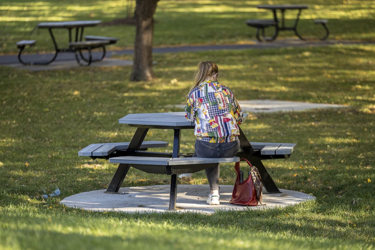 Photo d'une femme assise à une table dans le parc verdoyant