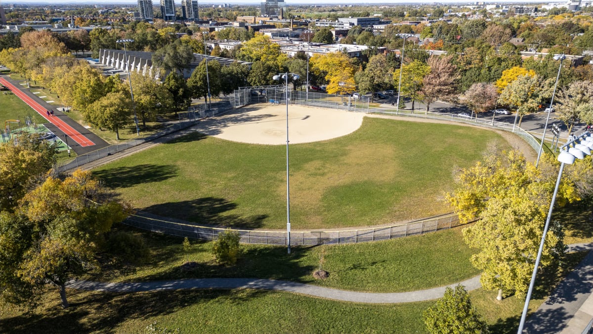 Vue aérienne montrant le terrain de balle entouré d'une clôture grillagée et surplombé de grands projecteurs lumineux.