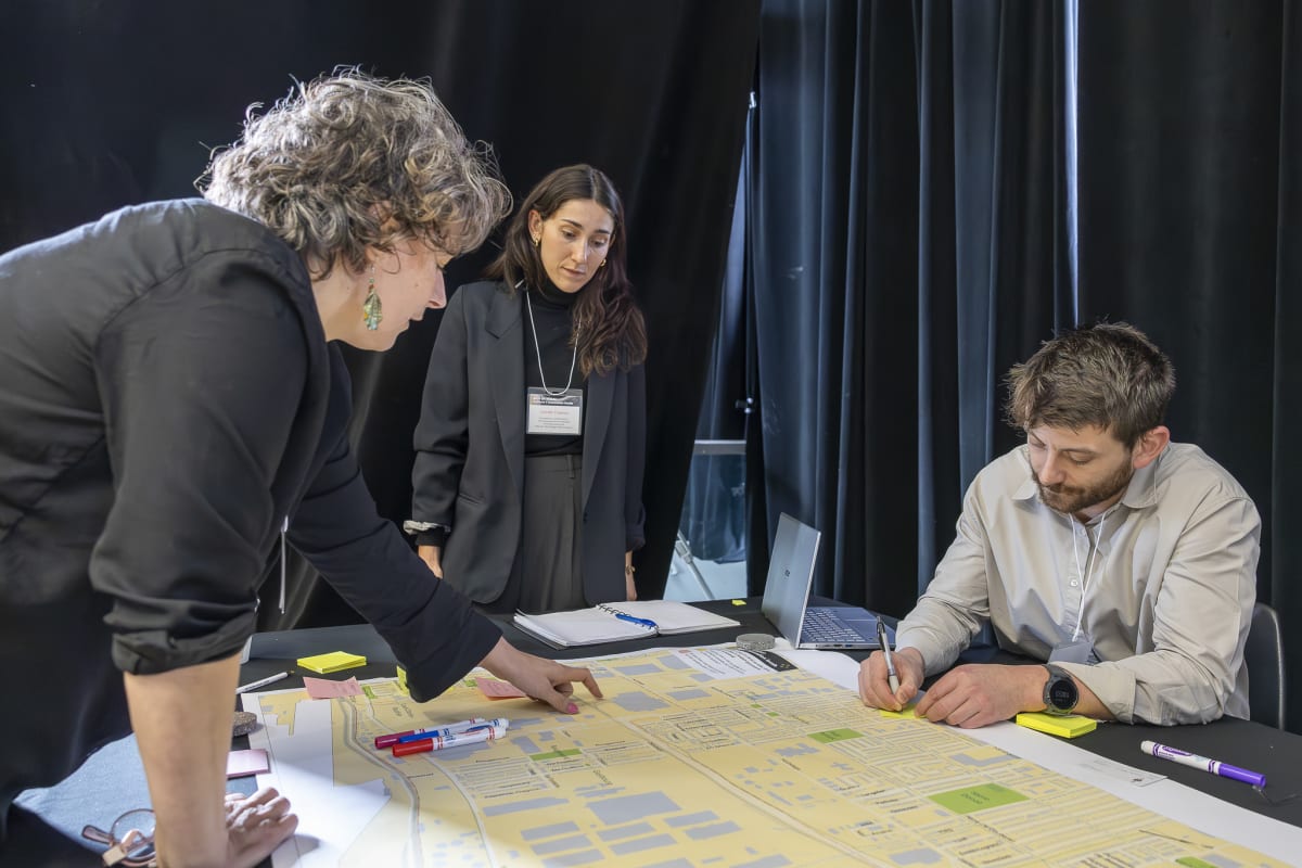 Photo d'un kiosque-atelier proposé lors de l'événement ASLP en réseau. On voit une participante commenter la carte d'Assomption Sud--Longue-Pointe et l'équipe de l'urbanisme de l'arrondissement qui note ses idées.