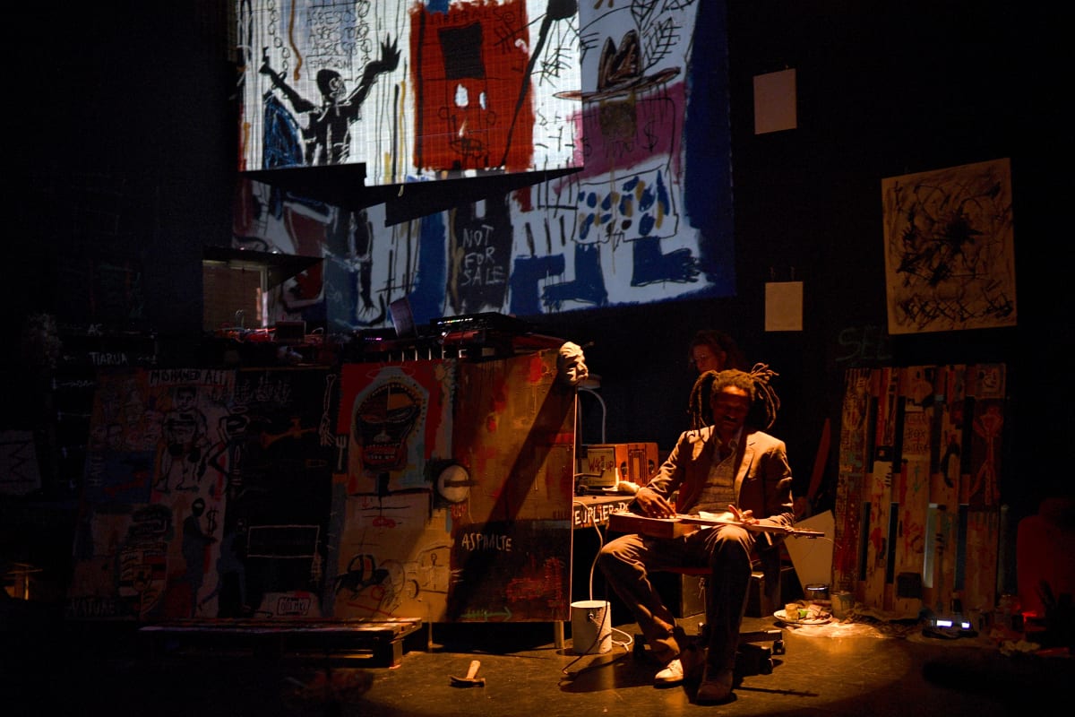 Une personne devant des toiles de Basquiat.